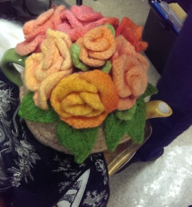 Tea cozy topped with knit flowers, which were hand painted with Kool-aid, just as one would marzipan. 